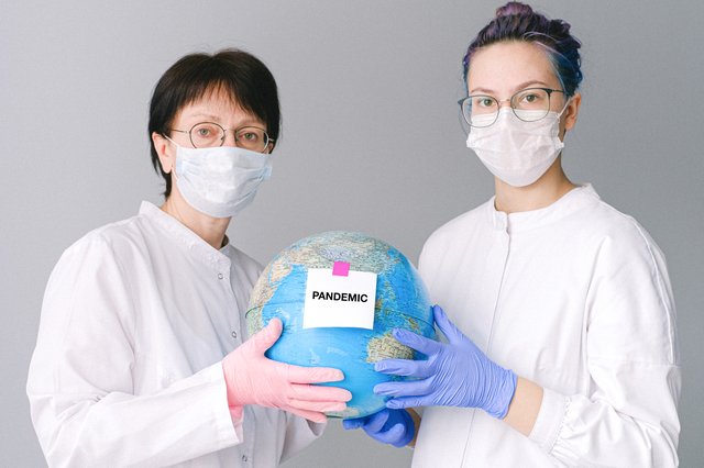 地球儀を掲げるマスク姿の女性二人